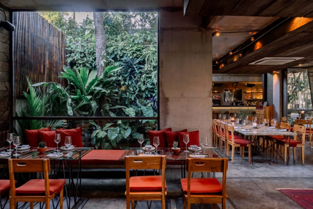 Restaurant dining area with tables set for meals, overlooking a lush green garden through a large window