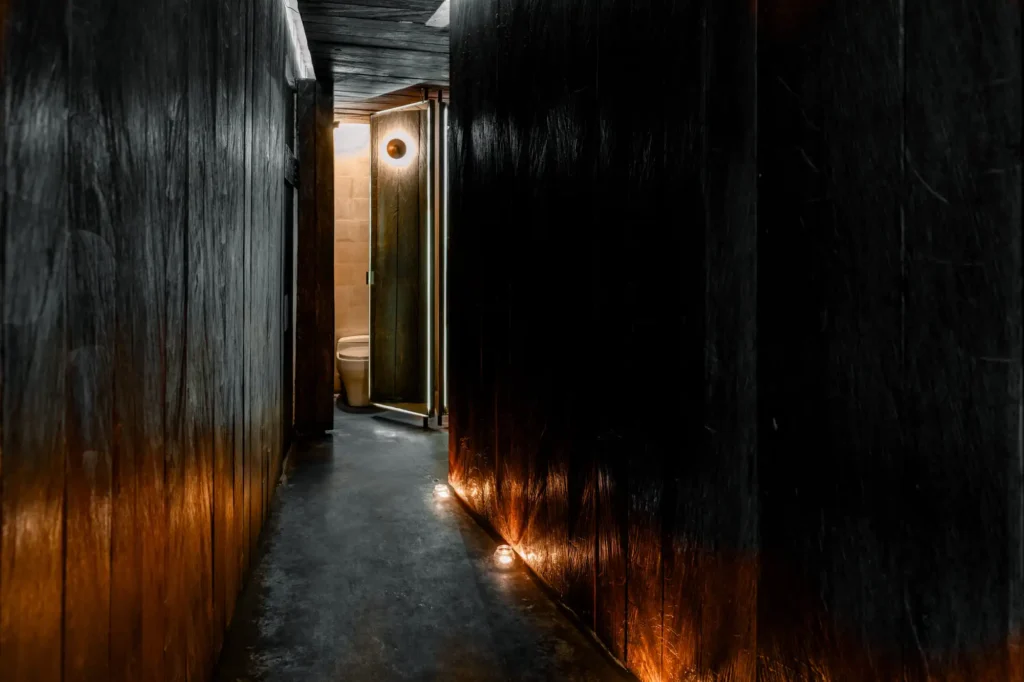 A shadowy corridor with a bright light shining on the wall, highlighting the depth of the dark space.