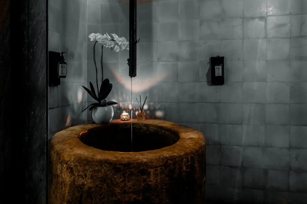 A bathroom featuring a sink and a decorative flower vase on the countertop, creating a serene atmosphere.