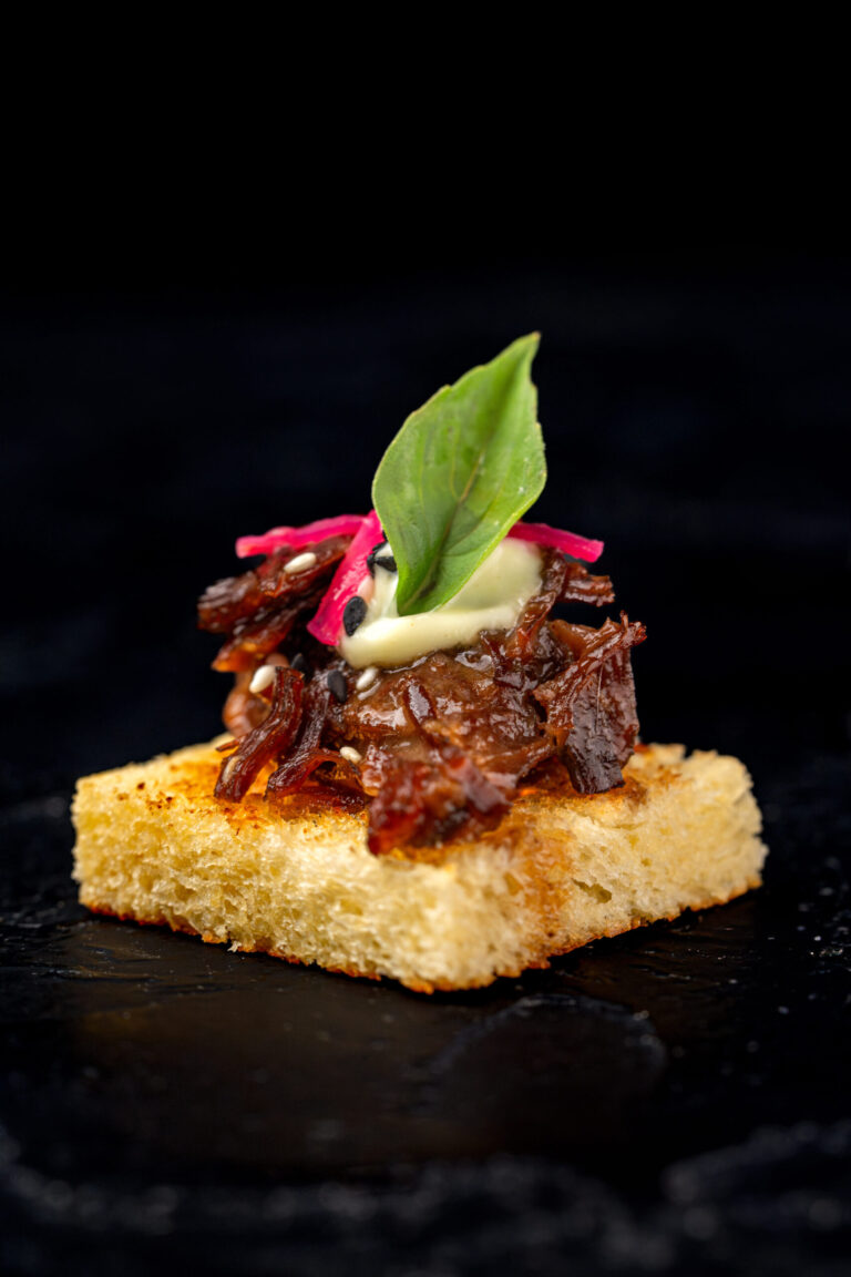 Braised beef canapé served on toasted bread.