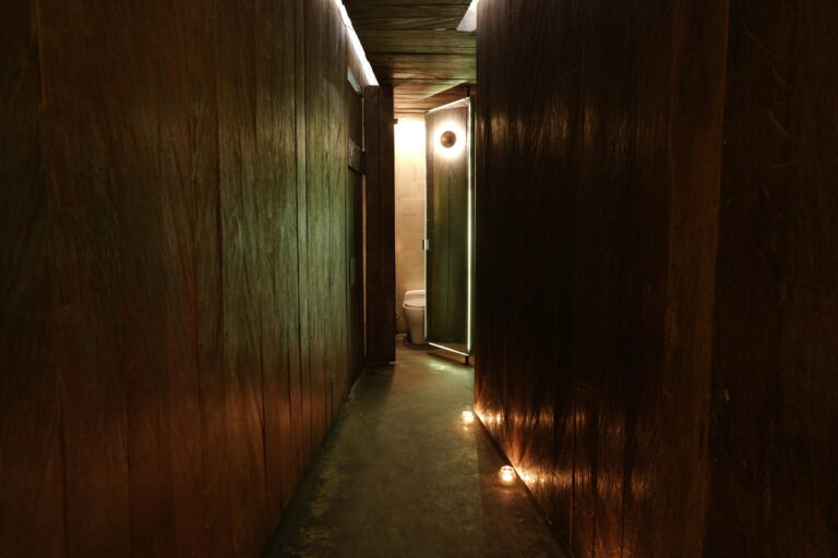 A dimly lit hallway illuminated by a soft light emanating from the wall, creating an eerie yet intriguing atmosphere.