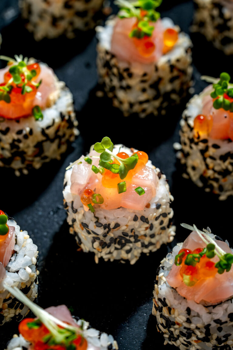 Bite-sized sushi topped with salmon and sesame seeds