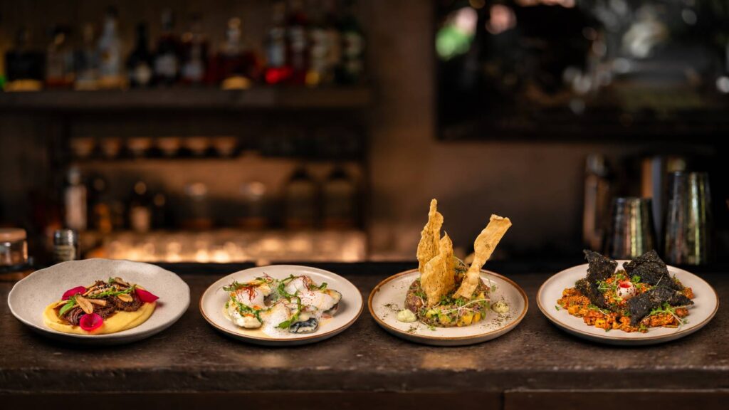 Four signature dishes beautifully presented on the bar counter at Kilo Kitchen Seminyak, Bali.