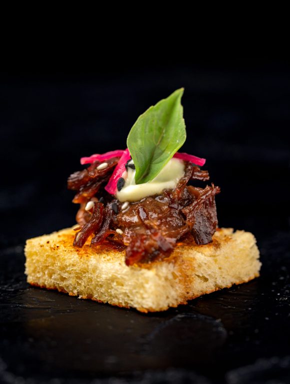 Braised beef canapé served on toasted bread.