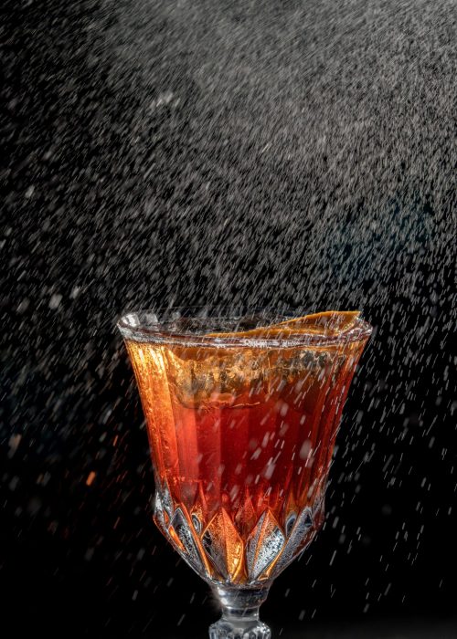A cocktail served with an ice ball and foam on top