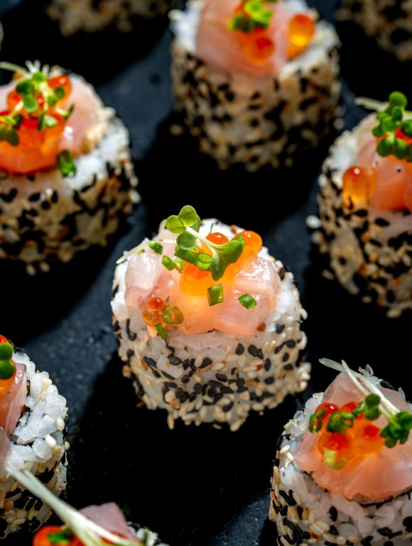 Bite-sized sushi topped with salmon and sesame seeds