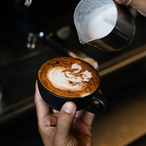 A freshly brewed coffee on a wooden tray with a cookie at Kilo Kitchen Seminyak