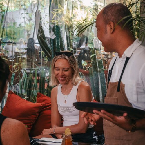 Server taking a guest's order in Kilo Kitchen Bali's relaxed dining space.