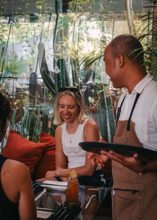 Server taking a guest's order in Kilo Kitchen Bali's relaxed dining space.
